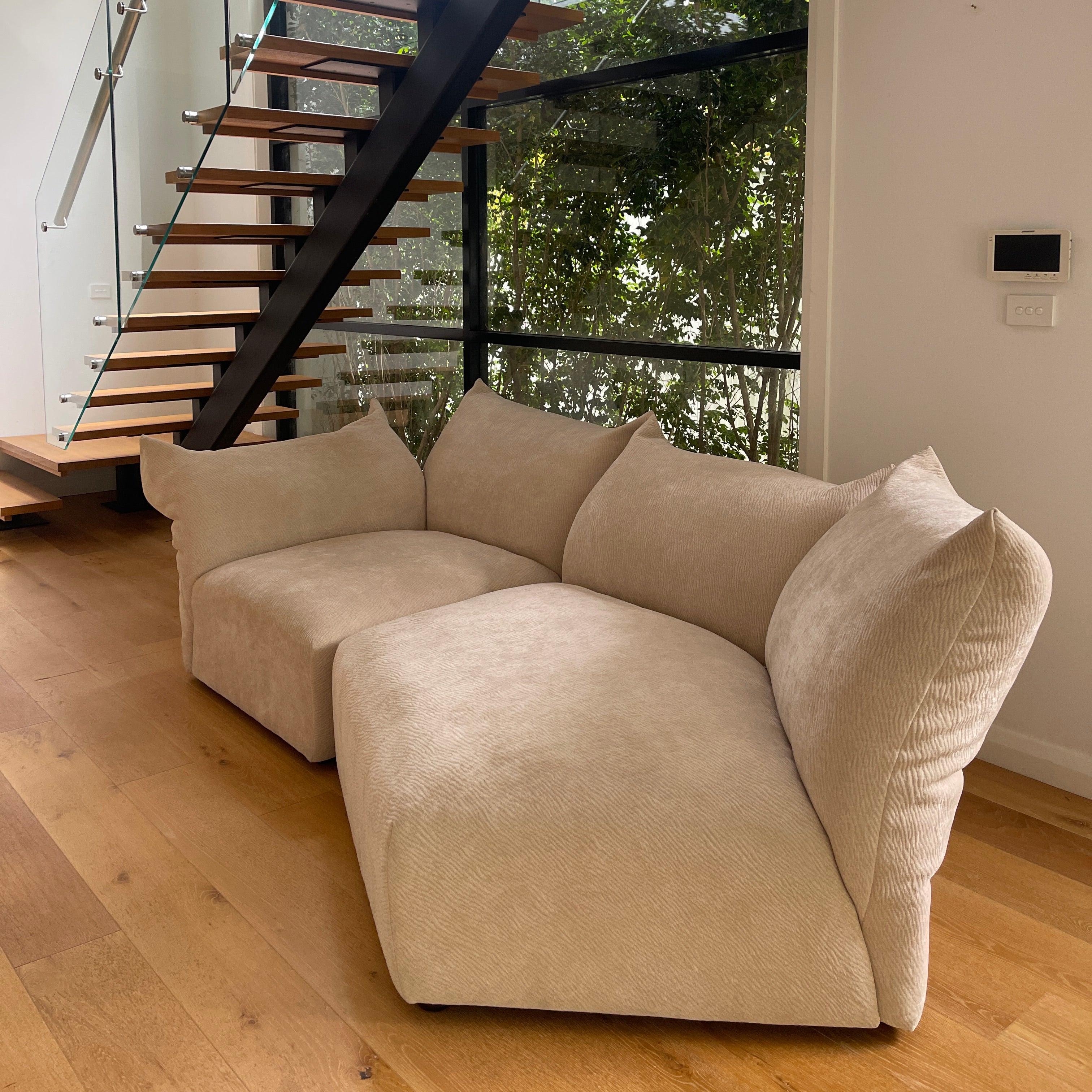 Beige sofa in a room with a staircase and glass wall
