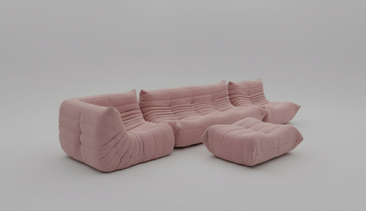 Pink sectional sofa in a minimalistic room with white walls and floor.