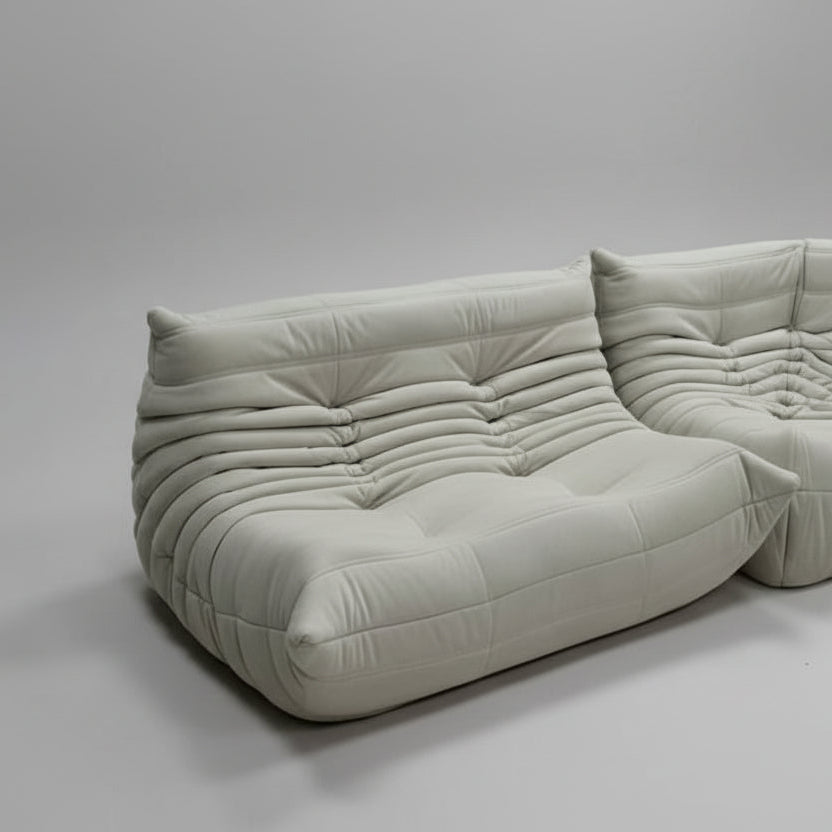 Gray sofa in a minimalistic room with white walls and floor.