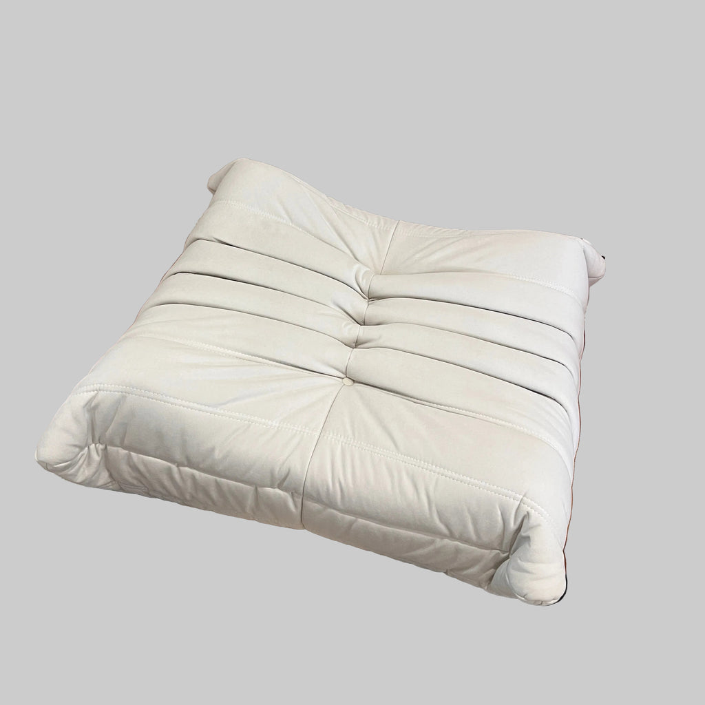 White cushion on a wooden floor next to a black and beige rug