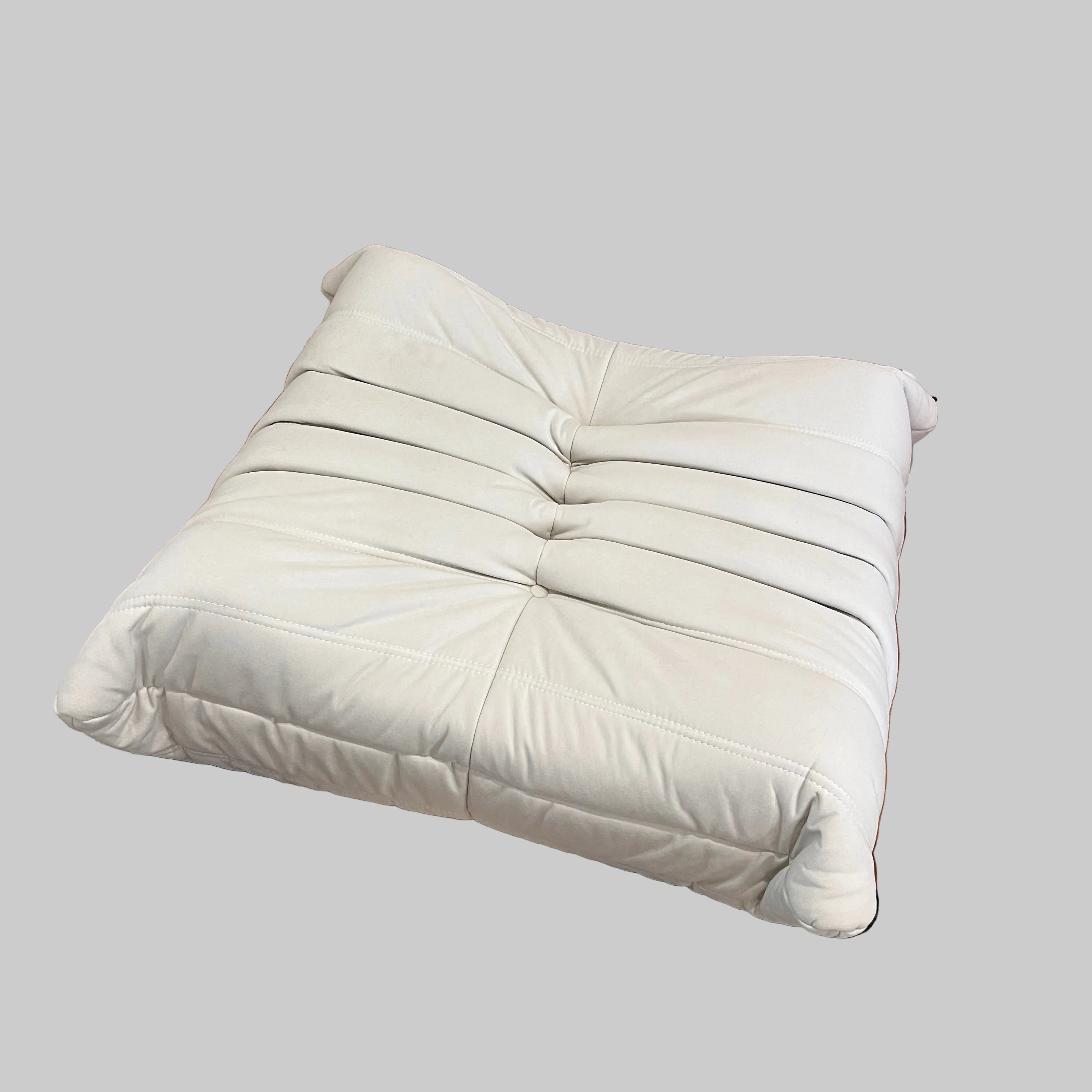 White cushion on a wooden floor next to a black and beige rug