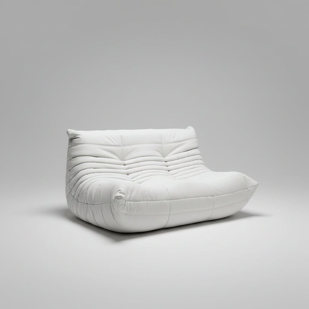 White cushioned bench against a wall with a painting of a building and abstract art.