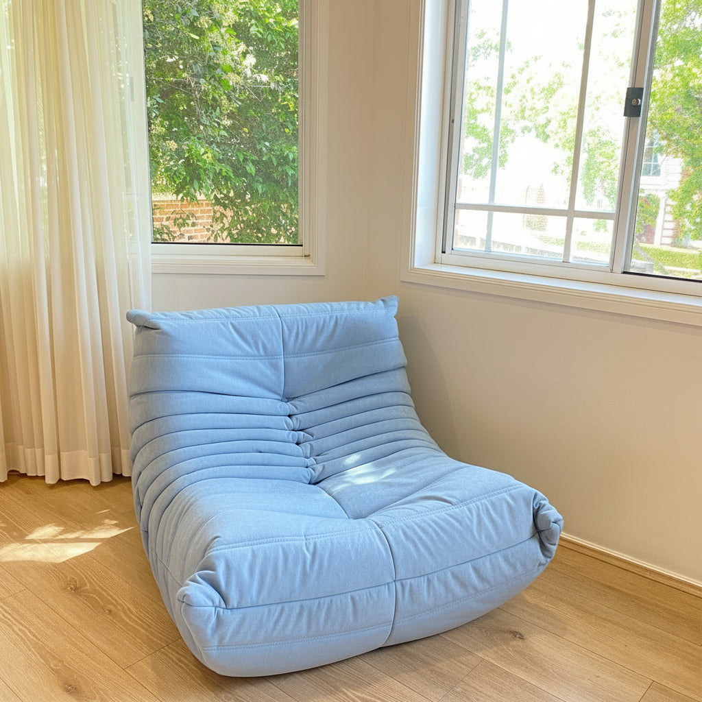 Light blue inflatable chair in a room with large windows and wooden floor.
