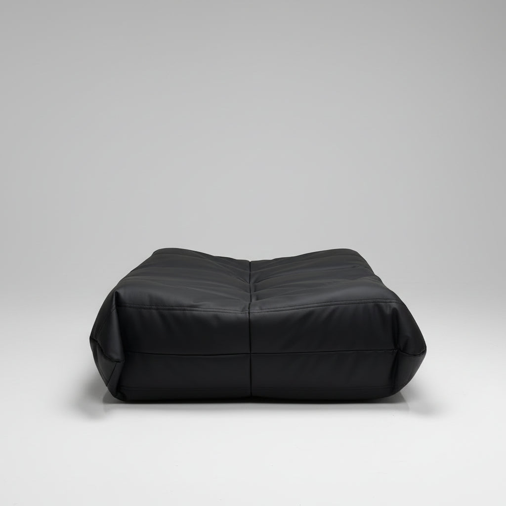 Black sofa against a wall with a colorful painting of a cityscape.