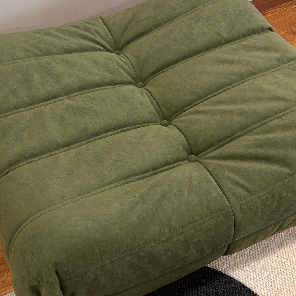 Green cushion on a chair with a black and white patterned rug in the background