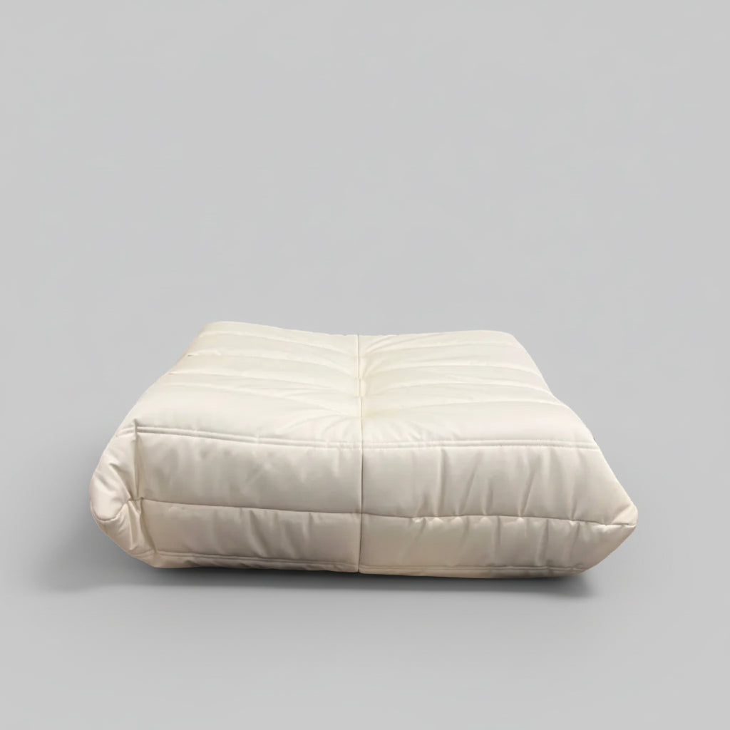 White upholstered headboard against a wall with a abstract black and white rug on the floor.