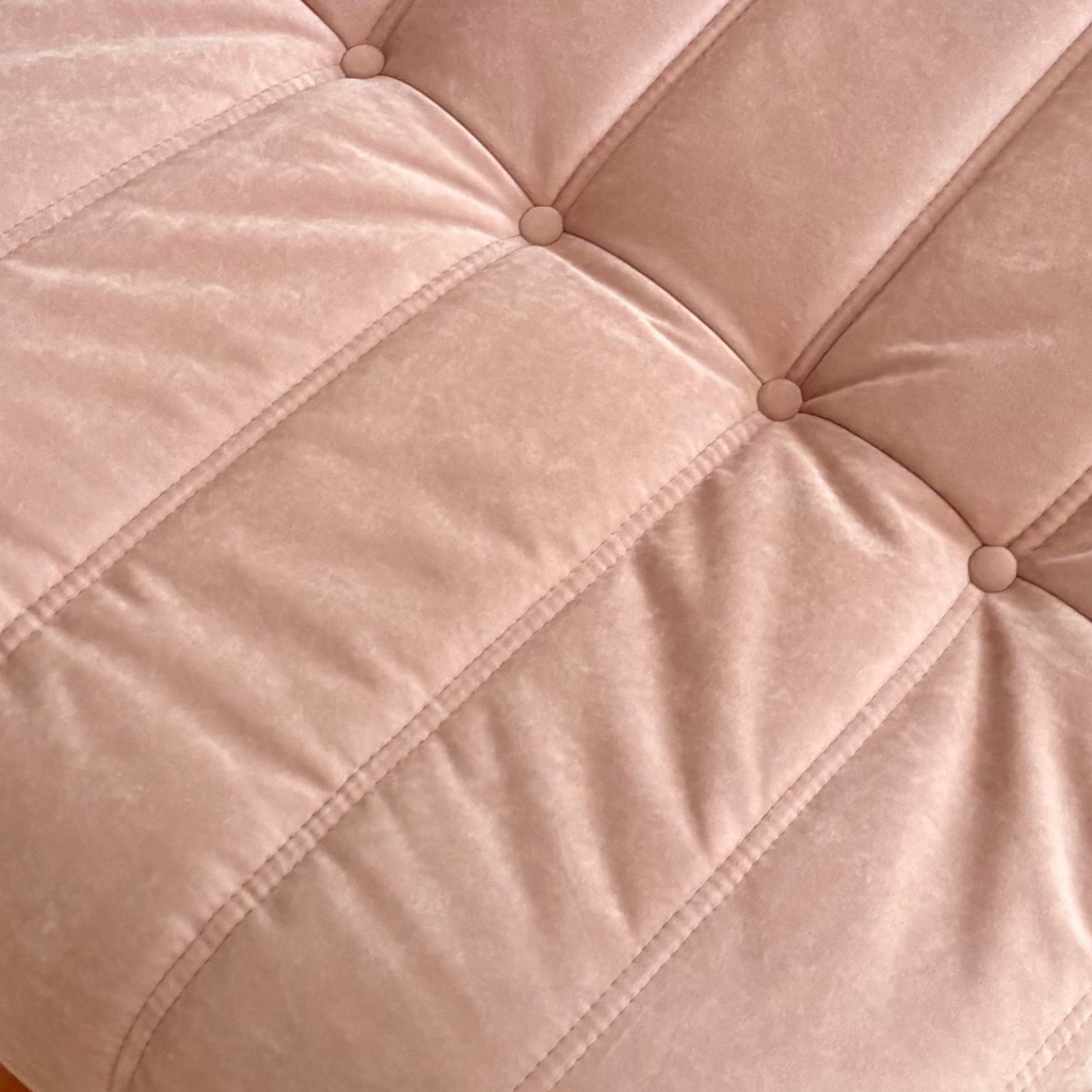 Pink cushion on a tiled floor with plastic bags in the background