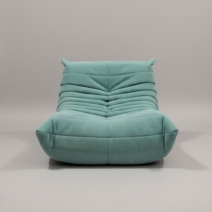 Light green bean bag chair on a patterned rug against a plain wall.