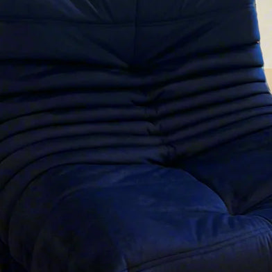 Person wearing a navy blazer sitting on a wooden floor with a window in the background