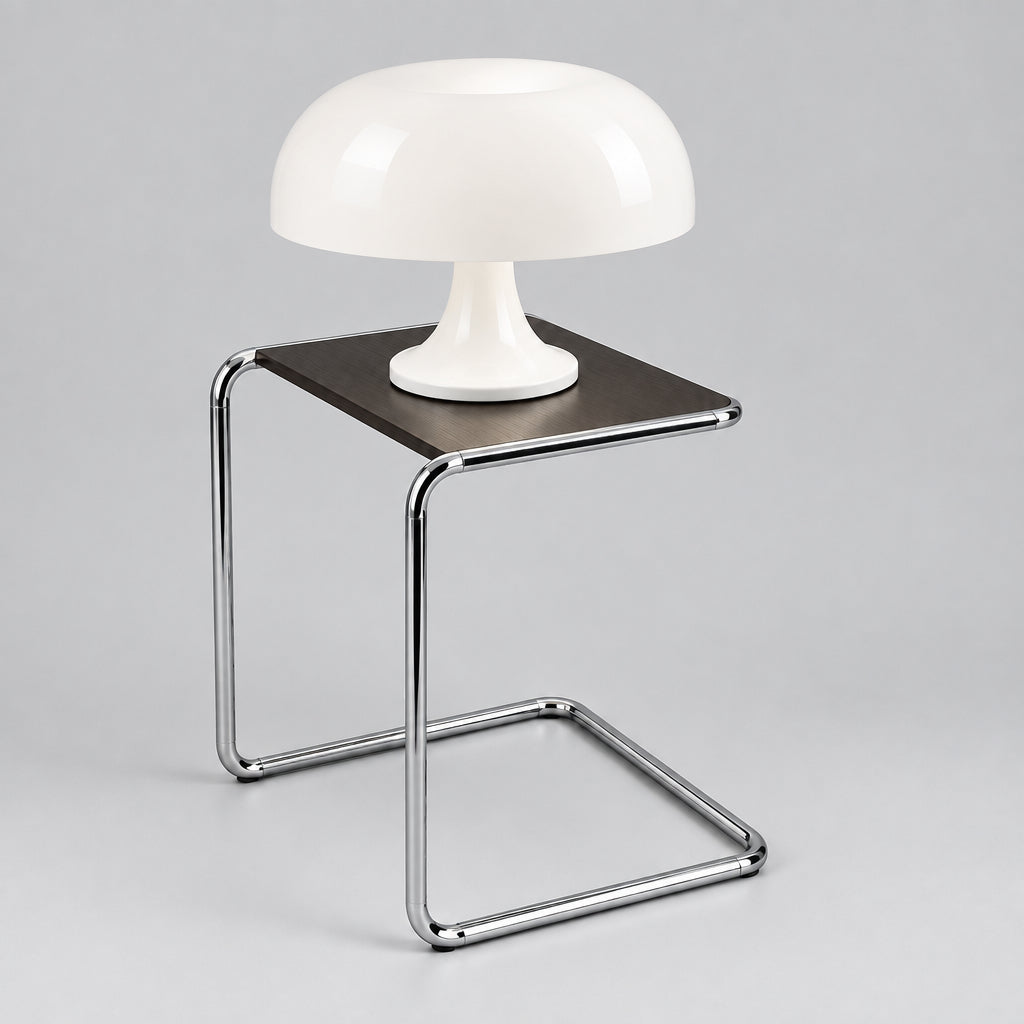 A mushroom-shaped table lamp with a white base sits on a square metal side table next to a gray sofa in a modern room setting.