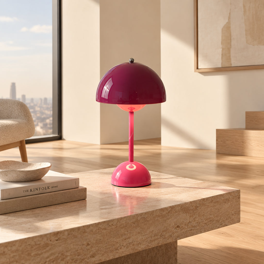 A mushroom-shaped pink table lamp glowing with warm light, shown next to a book and a small cup on a neutral studio background. Chinese text watermark is visible across the center.
