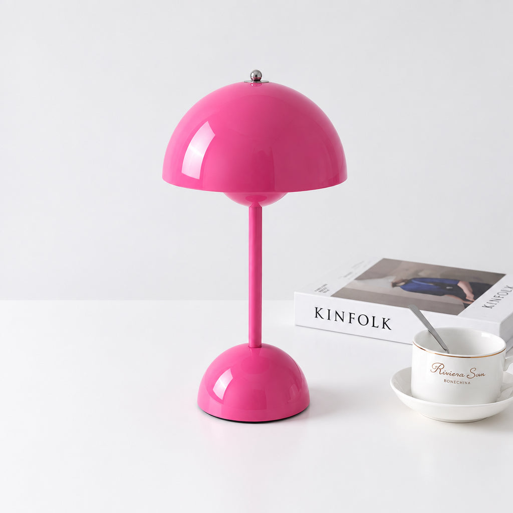 A glossy pink mushroom-shaped table lamp with a matching pink stem and base, shown on a light gray background next to a book and a small teacup and saucer. A Chinese watermark is visible across the center.