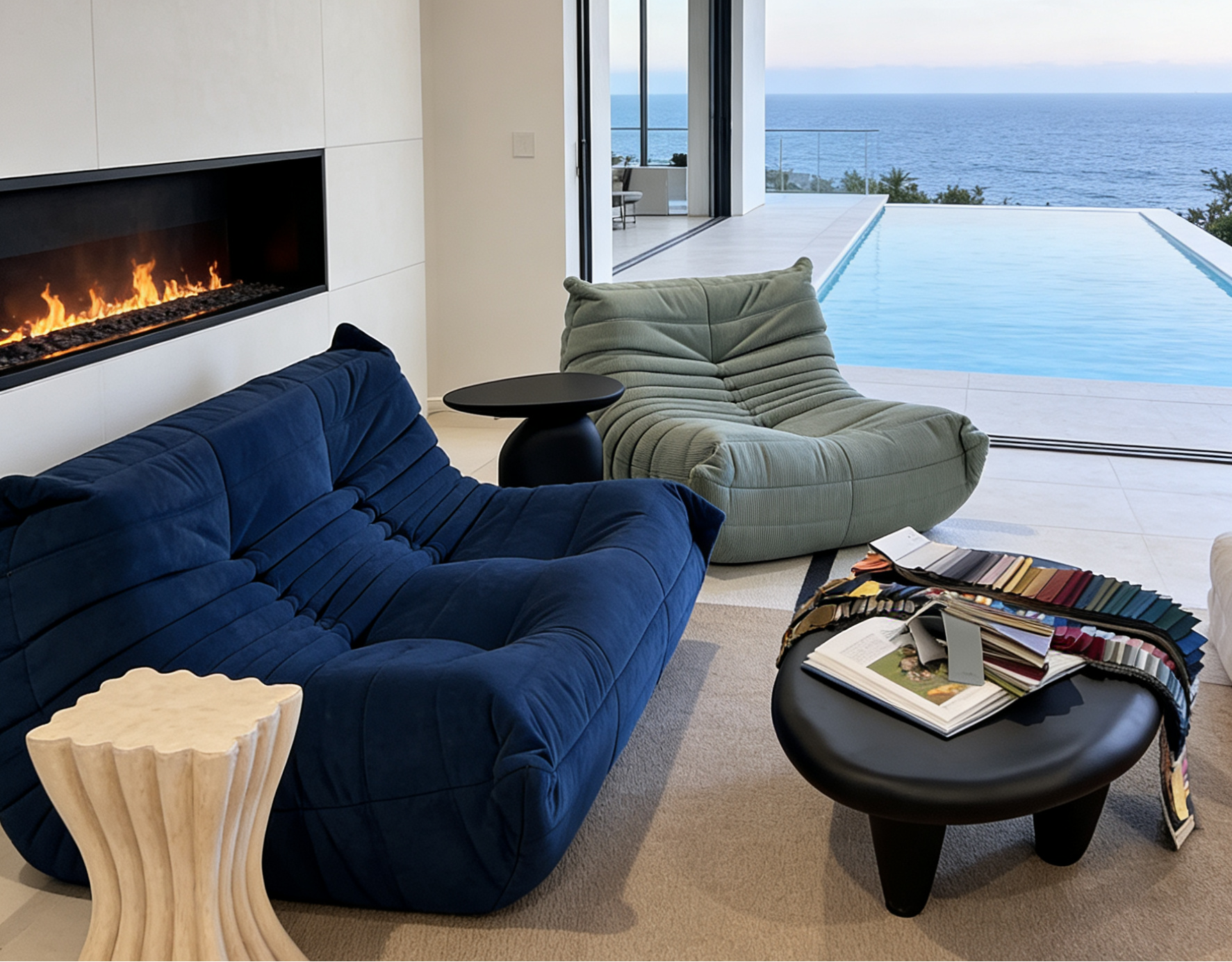Modern living room with blue sofa, green armchair, and fireplace overlooking a pool and ocean.