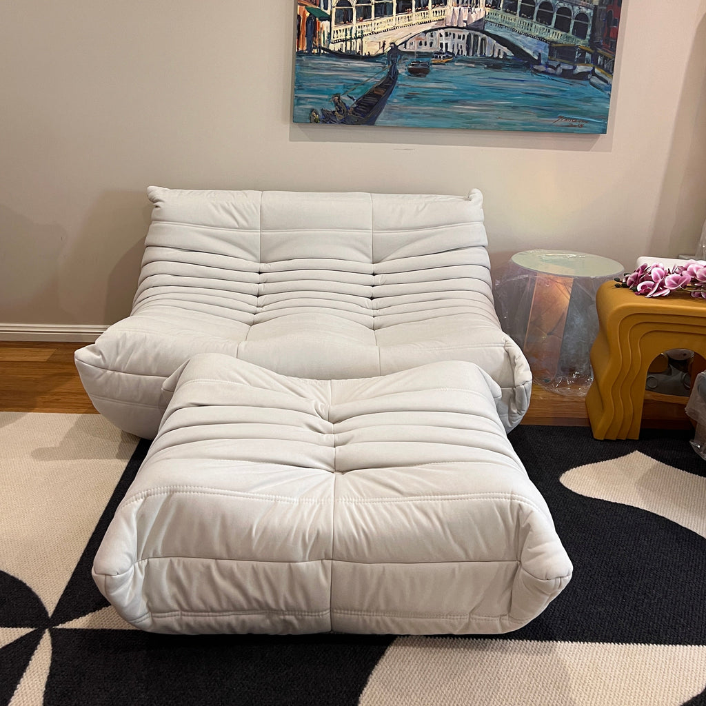 White upholstered chair against a wall with abstract art and a patterned rug.