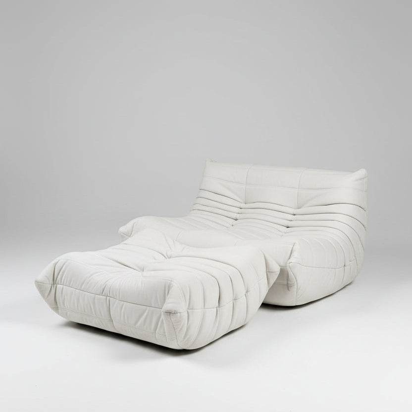 White upholstered headboard with textured surface on a bed, with a painting of a cityscape in the background.