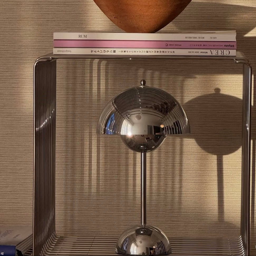 Decorative object on a shelf with a metallic finish against a textured wall.