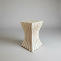 Decorative stone stool with wavy design on a neutral background