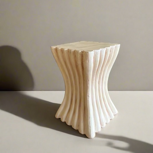 Decorative stone stool with wavy design on a neutral background