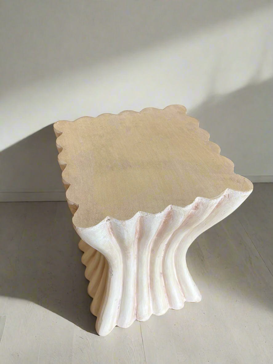 Decorative shell-shaped stool on a carpeted floor with a blue cushioned chair in the background.