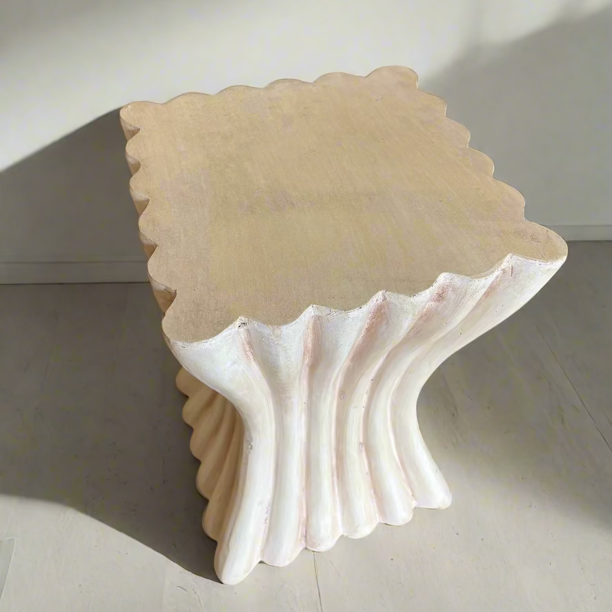 Decorative shell-shaped stool on a carpeted floor with a blue cushioned chair in the background.