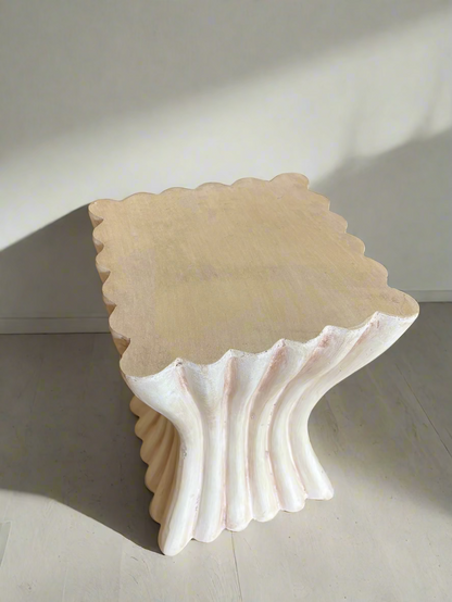 Decorative shell-shaped stool on a carpeted floor with a blue cushioned chair in the background.
