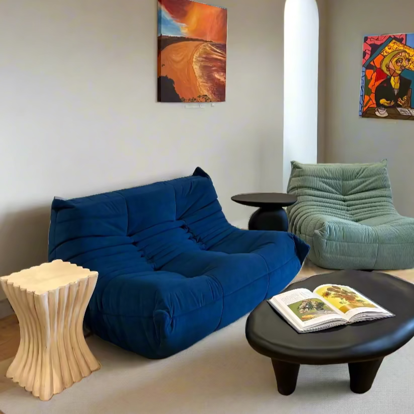 Modern living room with blue sofa, green chair, and colorful artwork on walls.
