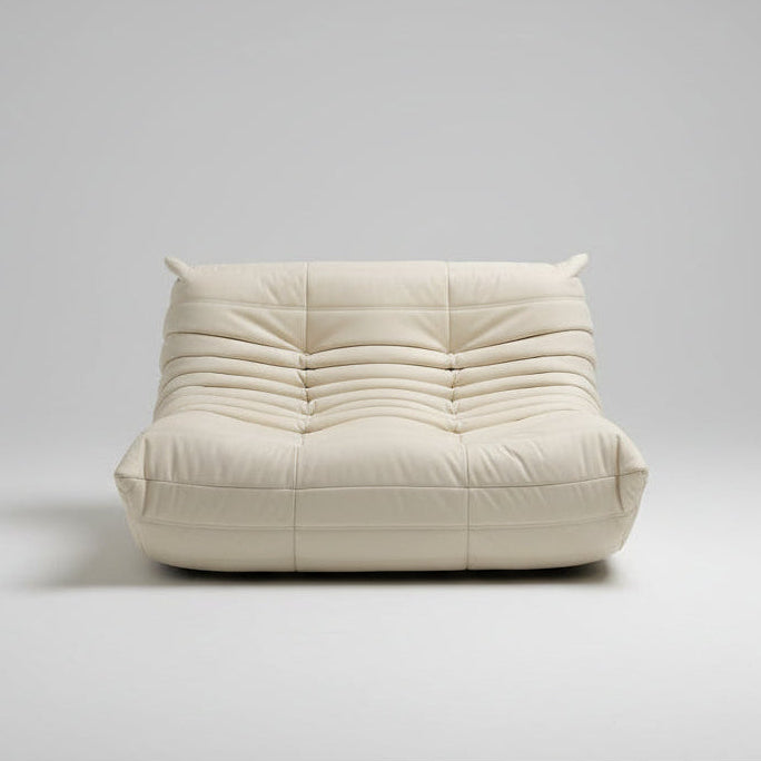 White cushioned chair in front of a glass door with a view of a pool and garden.