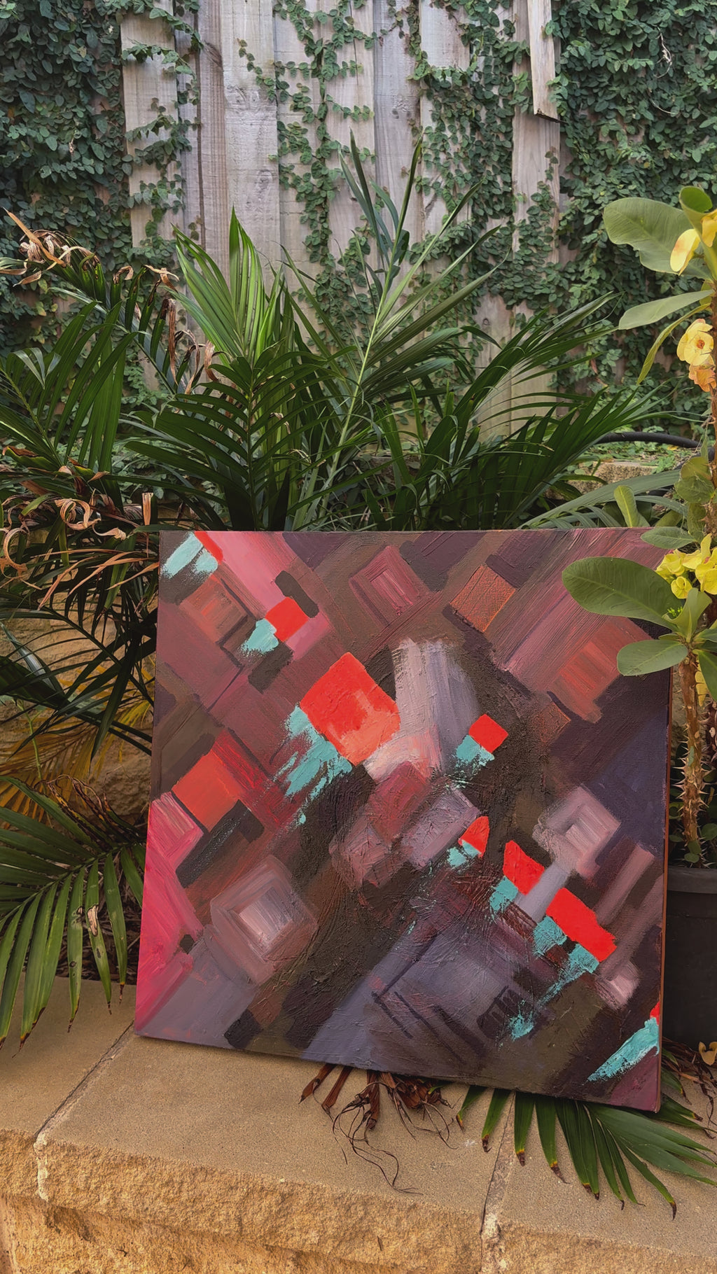 A modern abstract painting featuring geometric shapes in deep brown, red, and turquoise tones. Layered textures and bold brushstrokes create a dynamic, cityscape-inspired composition